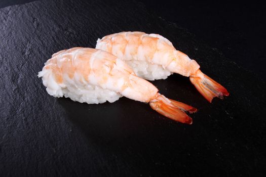 sushi on white plate, black background