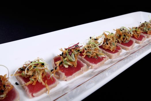 mixed sushi on white plate, black background