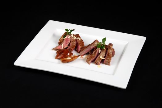 beef with mushrooms in white plate on a black background