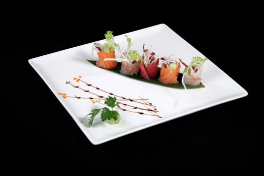 mixed sushi on white plate, black background