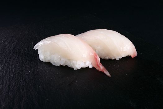 two sushi on black plate, black background