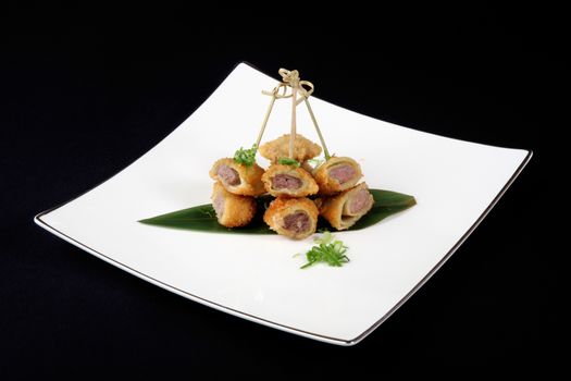 breaded fish with vegetables in white plate on black background