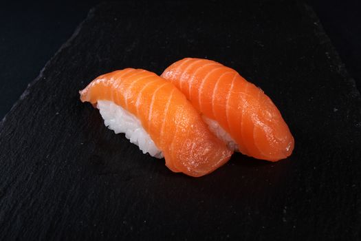 mixed sushi on white plate, black background