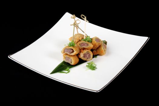 breaded fish with vegetables in white plate on black background