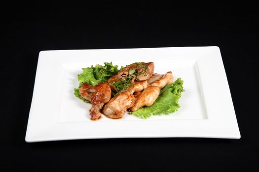 grilled chicken with vegetables in white plate on a black background