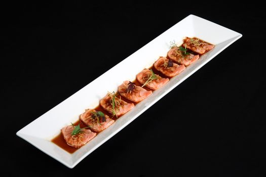 Salmon meat with sauce dish is white on black background