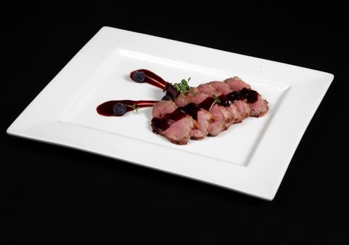 duck meat with cranberry cream in white plate on a black background