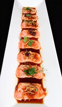 Salmon Steak with sauce and decoration of vegetables in white plate on a black background