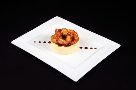 well dish with prawns in white plate on black background