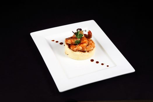 well dish with prawns in white plate on black background