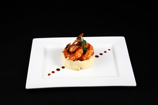 well dish with prawns in white plate on black background
