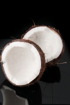 Coconut broken in half on a black background
