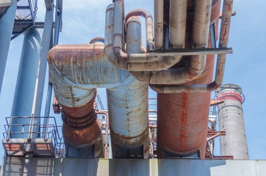 Industrial pipelines, pipelines in an old factory plant against blue sky.