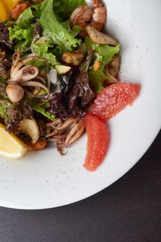 Closeup of vegetable salad with seafoods on white plate