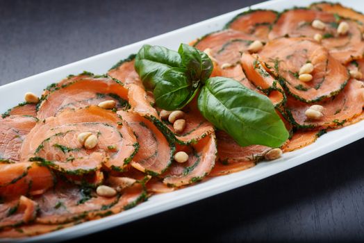 Salmon Carpaccio with nuts on white plate