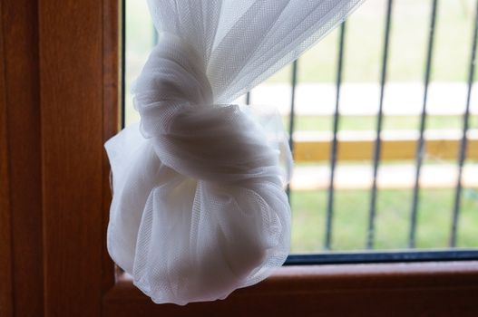 Hanging fine white curtain in front of a window