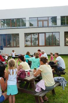 SIANOZETY, POLAND - JULY 22, 2015: People sitting on benches by wooden tables on a barbecue event