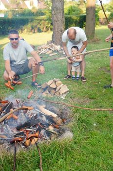 SIANOZETY, POLAND - JULY 22, 2015: People using stick to grill sausages on a fireplace at a barbecue event