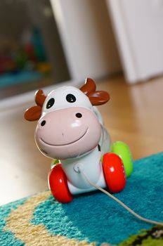 POZNAN, POLAND - AUGUST 20, 2015: Wheeled toy cow with pull rope on the floor