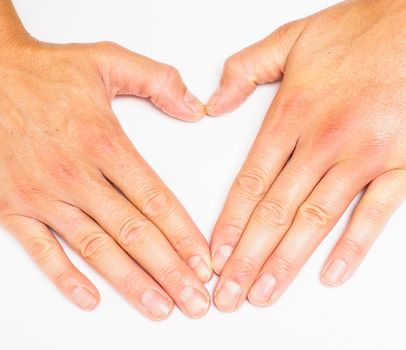 Adult person creating heart with hands towards grey white