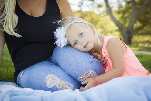 Beautiful Young Blue Eyed Girl Resting on Her Mommy's Lap Outside At the Park.