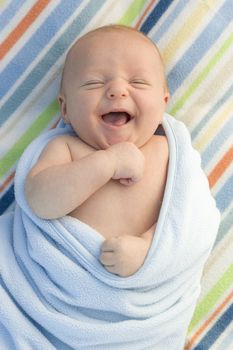 Beautiful Laughing Baby Boy Wrapped in His Blanket.