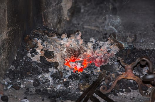 Embers and flame of a glowing red forge fire