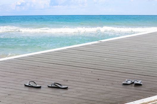 Black sandals on a boat dock on a promenade along the lake.
In the background, the blue sea.