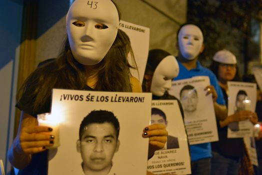 SPAIN, Madrid: Protesters wearing white masks rally outside the Embassy of Mexico in Madrid, Spain on September 25, 2015, while holding up signs displaying photographs of missing Mexican students who disappeared in Iguala, Mexico on September 26 last year. Forty-six students who attended Ayotzinapa Rural Teachers' College went missing with the circumstances surrounding their disappearance still unclear