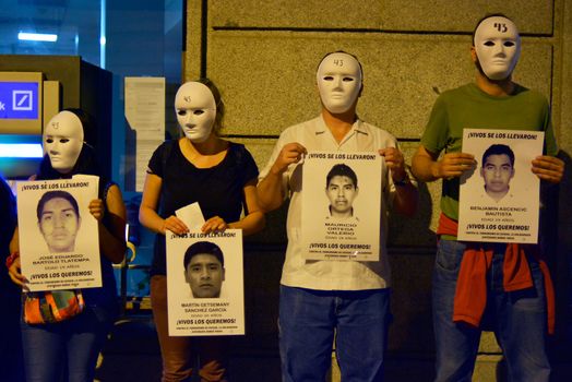 SPAIN, Madrid: Protesters wearing white masks rally outside the Embassy of Mexico in Madrid, Spain on September 25, 2015, while holding up signs displaying photographs of missing Mexican students who disappeared in Iguala, Mexico on September 26 last year. Forty-six students who attended Ayotzinapa Rural Teachers' College went missing with the circumstances surrounding their disappearance still unclear