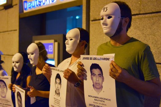 SPAIN, Madrid: Protesters wearing white masks rally outside the Embassy of Mexico in Madrid, Spain on September 25, 2015, while holding up signs displaying photographs of missing Mexican students who disappeared in Iguala, Mexico on September 26 last year. Forty-six students who attended Ayotzinapa Rural Teachers' College went missing with the circumstances surrounding their disappearance still unclear