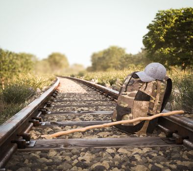 Railway track crossing rural landscape with travel backpack