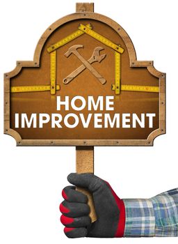 Hand with work glove holding a wooden sign with a meter ruler in the shape of house with text Home Improvement. Isolated on white background