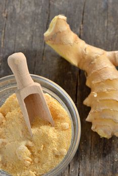 Fresh ginger root and ground ginger spice on wooden table
