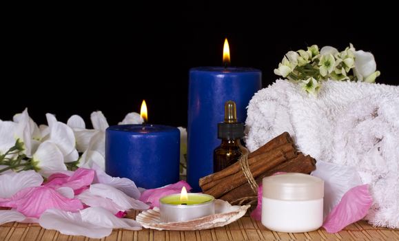 Towels, massage oil and candles on a black background
