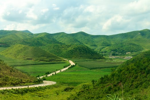 Mountain road in North Korea. Mountains covered with green vegetation.