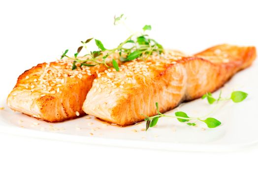 Grilled salmon, sesame seeds  and marjoram on white plate. Studio shot