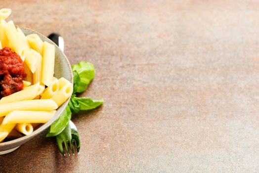 Penne pasta with a tomato bolognese beef sauce on the table, with copy space