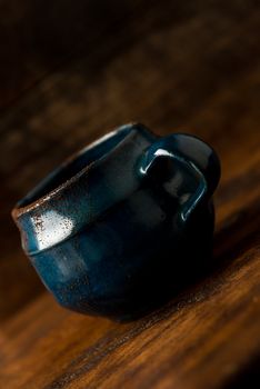 Coffee in grunge blue clay cup on rustic wooden background