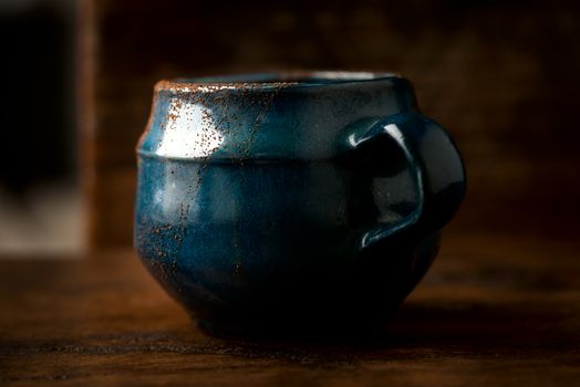 Coffee in grunge blue clay cup on rustic wooden background