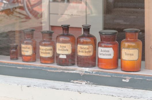 Historic old pharmacy bottles with label in a shop window.