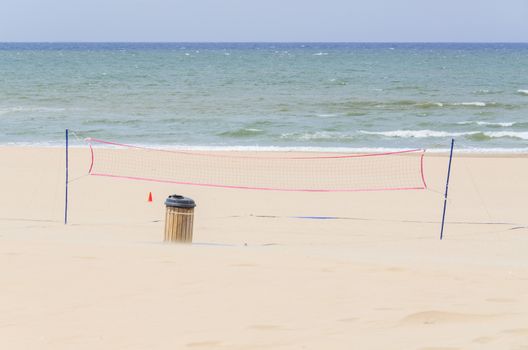 Beach volleyball net in the background of the blue sea and a cloudless sky.