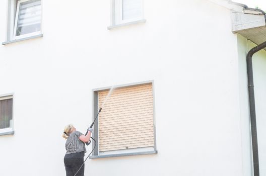 Exterior cleaning and building cleaning a gable wall with high pressure water jet.