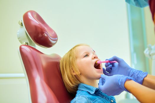 Little patient at the dentist office. The dentist brushes teeth to the little girl