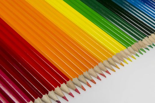 Abstract composition of a set wooden colour pencils against a white background
