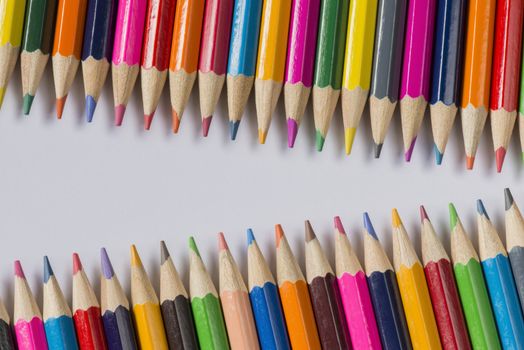 Abstract composition of a set wooden colour pencils against a white background
