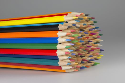 Abstract composition of a set wooden colour pencils against a white background
