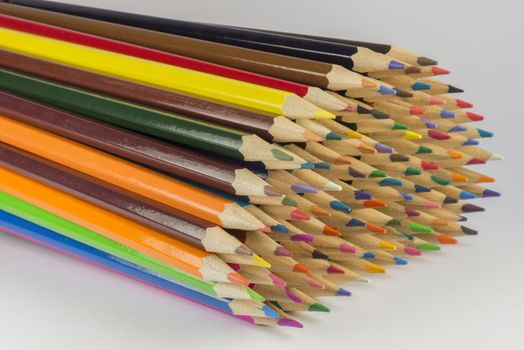 Abstract composition of a set wooden colour pencils against a white background
