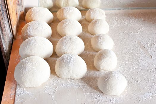 Rows of pizza dough on table ready to be made into a pizza base