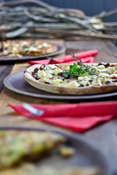 Three pizzas laid out on wooden trays on a wooden tables in a pizzeria.